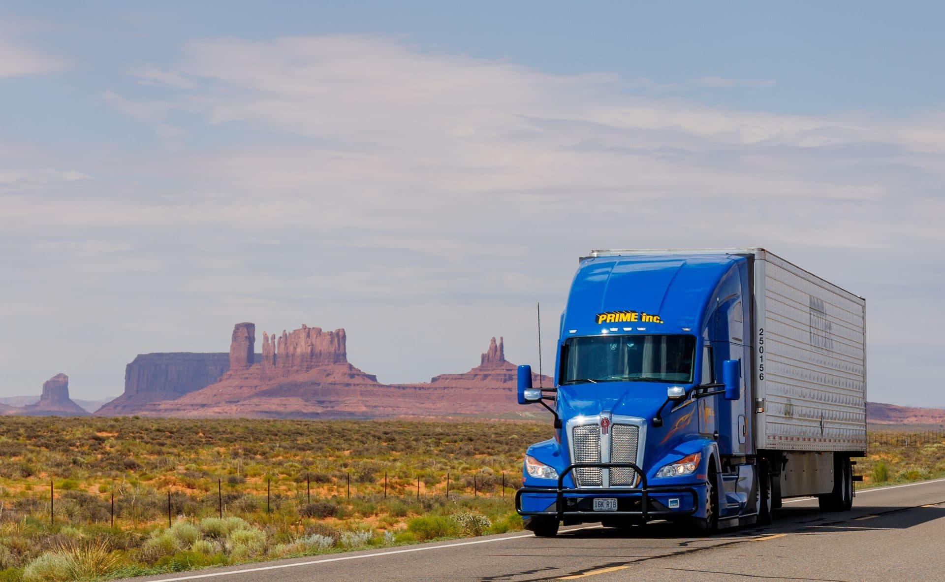 Blue Kenworth pulling a dry van past the red buttes of the desert Southwest