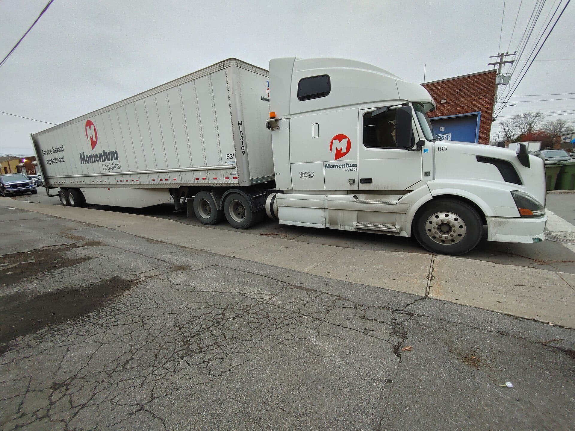 White Volvo tractor backing a dry van trailer across a lot