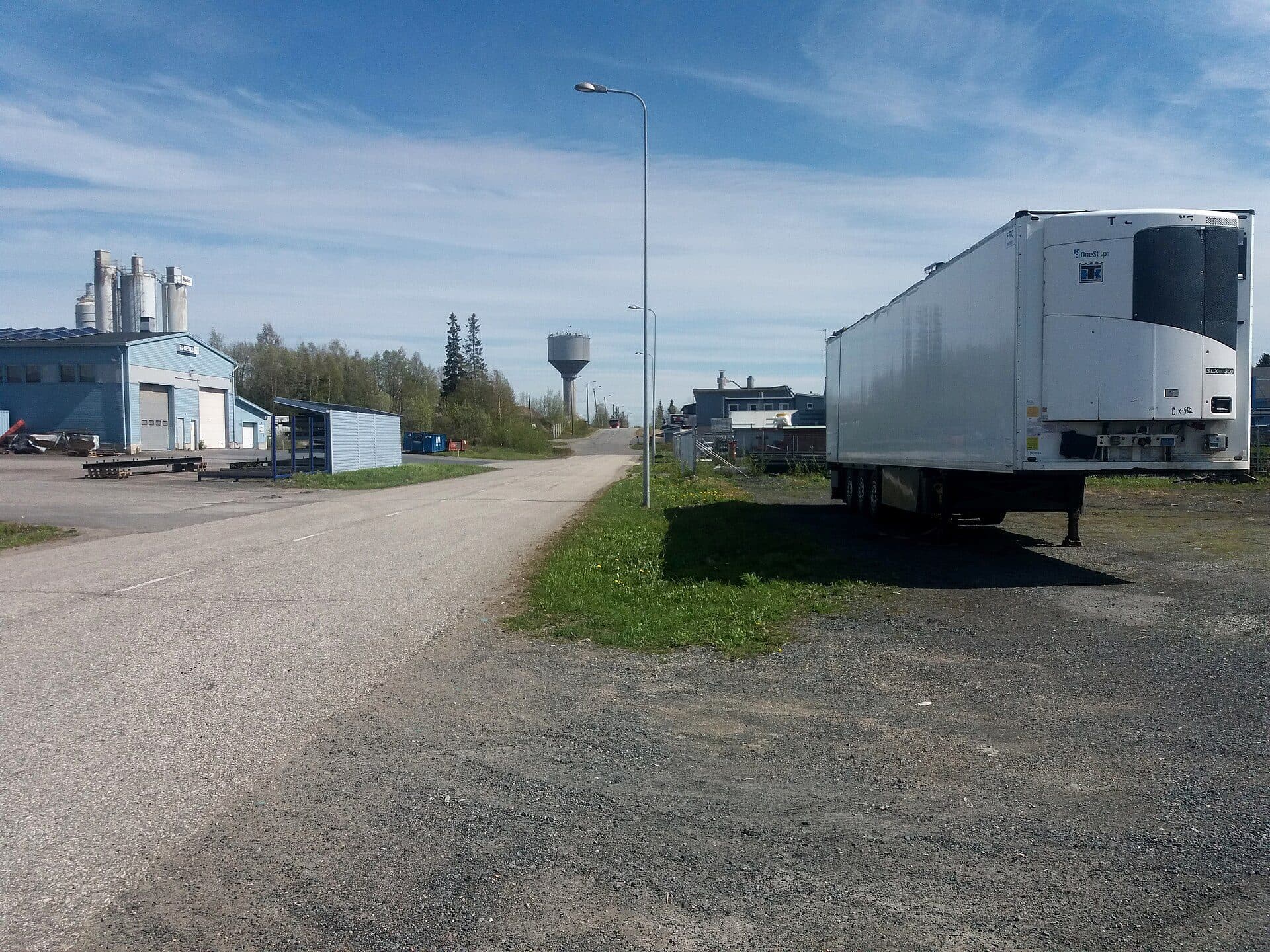 Detached refrigerated trailer parked beside a rural road